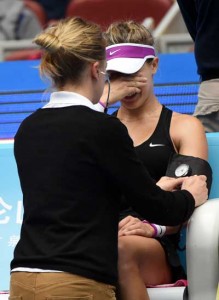Eugenie Bouchard (right) of Canada receives medical attention during her first round women’s singles match against Andrea Petkovic of Germany at the China Open tennis tournament in Beijing. AFP PHOTO