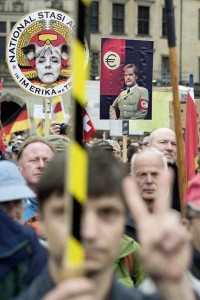 MIGRANTS NOT WELCOME  Supporters of the German right-wing movement PEGIDA (Patriotic Europeans Against the Islamization of the Occident) hold up a poster showing German Chancellor Angela Merkel in a uniform with an Euro-logo-armband as they attend a PEGIDA rally on June 1 in Dresden, Germany. They gather in the dark, wave German flags and vent their fury at foreigners they fear are overrunning their homeland — next week Germany’s anti-Islamic PEGIDA movement turns one year old. AFP PHOTO