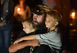 A man, who declined to give his name, holds his sons during a vigil in Roseburg, Oregon for ten people killed and seven others wounded in a shooting at a community college in the western US state of Oregon. AFP PHOTO