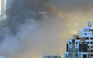 BIG FIRE Smoke rises as a rescue helicopter (top) uses a water bucket to help douse the flames of a fire that broke out in an informal settlers area in Mandaluyong City. AFP PHOTO 