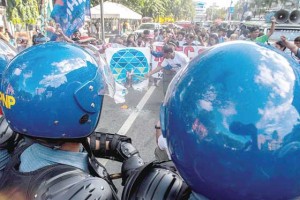 LAST DAY HIGH  Activists sets an APEC logo on fire to dramatize their indignation over the holding of the annual meeting in Manila as police in riot gear look on. PHOTO BY DJ DIOSINA