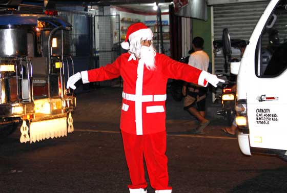 Night time motorists and commuters find this five-foot man in Santa Claus suit amusing as he directs traffic along the busy McArthur Highway in Tarlac City. He may not be bringing gifts and goodies but he lessens tension on the road because of traffic congestion. PHOTO BY MIKE DE JUAN