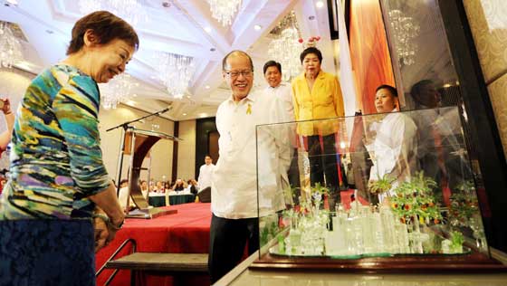 President Benigno Aquino 3rd views the miniature ‘Tuwid Na Daan’ made of glass presented as a gift to the President by organizers of  Bulong Pulungan at  the annual Bulong Pulungan  Christmas Party. MALACAÑANG PHOTO