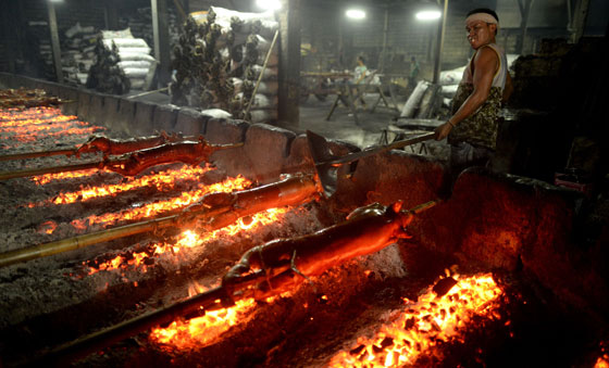 A worker arranges coals being used to roast bamboo-skewered pigs in Manila on Christmas eve. “Lechon” or roasted pig, is a regular fare at Philippine festivities, especially during Christmas and New Year celebrations. AFP PHOTO 