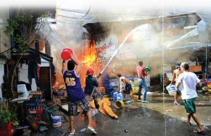 USEFUL PAILS Residents using plastic containers filled with water try to put out a fire after the blaze gutted a shanty town near a jail building in Manila on Friday.  AFP PHOTO