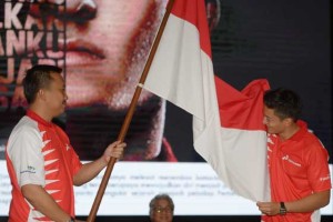 Indonesian Rio Haryanto (right) kisses the national flag next to Sport and Youth Minister Imam Nachrowi (left) during a press conference in Jakarta on February 18, 2016. Haryanto, the first Indonesian driver in Formula One, will join British Formula One team Manor in 2016. AFP PHOTO 