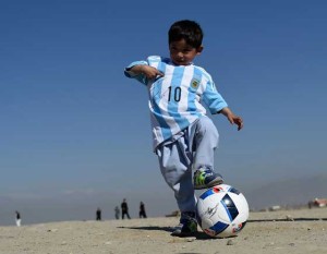 Afghan boy five-year-old Murtaza Ahmadi, a young Lionel Messi fan, plays football as he wears a donated and signed shirt by Messi on a field in Kabul on Friday. AFP PHOTO 