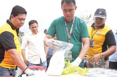 A police investigator examines the five kilos of shabu seized in Manila as Interior Secretary Mel Senen Bacani looks on. PHOTO BY CZEASAR DANCEL