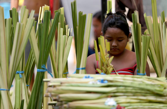  A girl ties palm fronds on a street in Manila on the eve of Palm Sunday. Catholics all over the world mark the start of holy Week today. Photo By RUSSELL PALMA