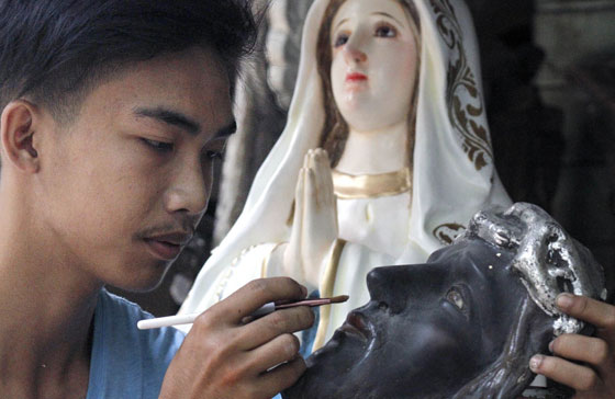 Must have Jomarie Yumol puts finishing touches on a wooden image of Jesus Christ in his Quezon City shop. Demand for these sculpted images rises during Holy Week, when Catholics pause to reflect on the death and resurrection of Jesus Christ. Photo by Mike De Juan