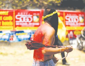 TIME TO ADVERTISE This photo taken on Friday shows a flagellant near advertisement tarpaulins at the village of San Pedro Cutud in the outskirts of San Fernando, Pampanga province, north of Manila. AFP PHOTO