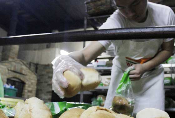 A baker packs finished bread products at a bakery in Quezon City. The Department of Trade and Industry announced that major bread manufacturers will cut prices of loaf bread and pandesal by P0.50 per item because of a decrease in prices of raw materials.  Photo by Mike de Juan