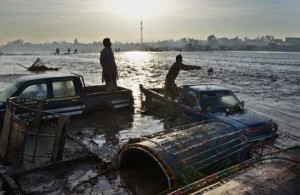 Pakistani men stand over their vehicles submerged by floodwater following heavy rain on the outskirts of Peshawar on April 4. At least 53 people were killed and 60 injured after heavy rain across northwest Pakistan and areas of Kashmir caused landslides and the roofs of dozens of homes to collapse, officials said. AFP PHOTO