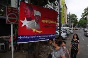 People walk past a commercial billboard by a local food company with portraits of Myanmar democracy figurehead Aung San Suu Kyi and President Htin Kyaw displayed on a street in Yangon on April 18. AFP PHOTO