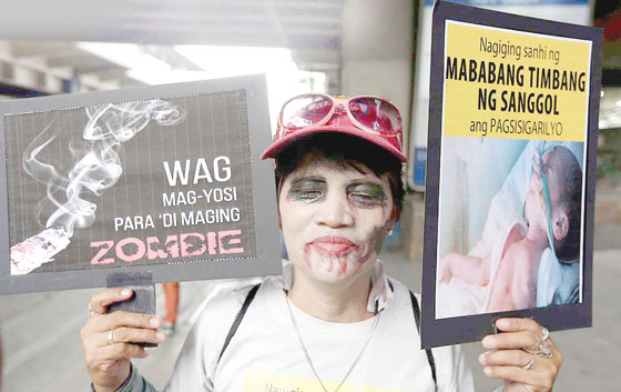  A member of Health Justice holds placards to warn the public on the dangers of smoking at the MRT station in Kamuning, Quezon City to mark World Tobacco Day. PHOTO BY MIKE DE JUAN