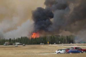 SEEKING REFUGE A convoy of evacuees drives south as flames and smoke rises along the highway near near Fort McMurray, Alberta on Friday (Saturday in Manila). AFP PHOTO