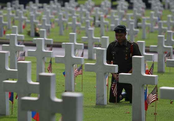 A soldier prays in front of a cross marking the grave of a fallencomrade at the Manila Memorial Cemetery in Taguig City (Metro Manila) as the country marked Memorial Day. PHOTO BY RUSSELL PALMA