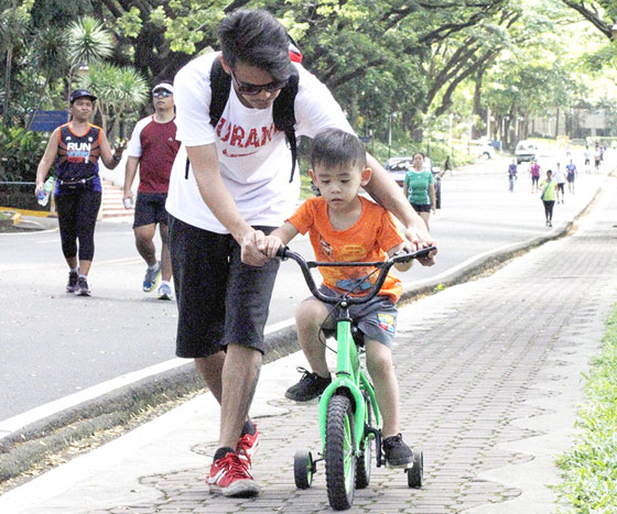 A boy learns how to ride a bike from his father at the University of the Philippines’ oval in Quezon City. Today, fathers will be the center of attention as the country celebrates Father’s Day. PHOTO BY MIKE DE JUAN