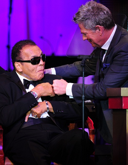 This file photo taken on March 24, 2012 shows Director David Foster (R) bumping fists with boxing legend Muhammad Ali on stage at the Muhammad Ali's Celebrity Fight Night XVIII in Phoenix, Arizona. The event supports the fight against Parkinson's disease and this year also celebrates Ali's 70th birthday. AFP PHOTO 