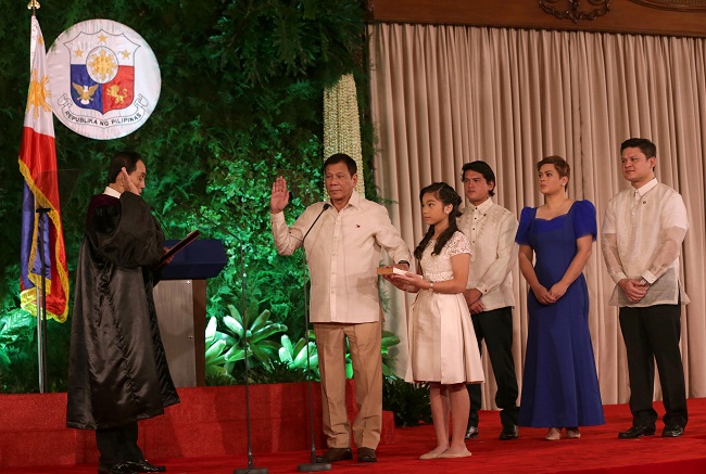 In this handout taken on Thursday and released by the Presidential Communication Operations Office (PCOO) Phillippine President Rodrigo Duterte (R) is sworn-in by Supreme court associate justice Bienvenido Reyes (L) while his daughter Veronica Duterte holds the bible and other children (back L-R) Sebastian Duterte, Sara Duterte and Paolo Duterte look on during the oath-taking ceremony in Malacañang. AFP PHOTO 