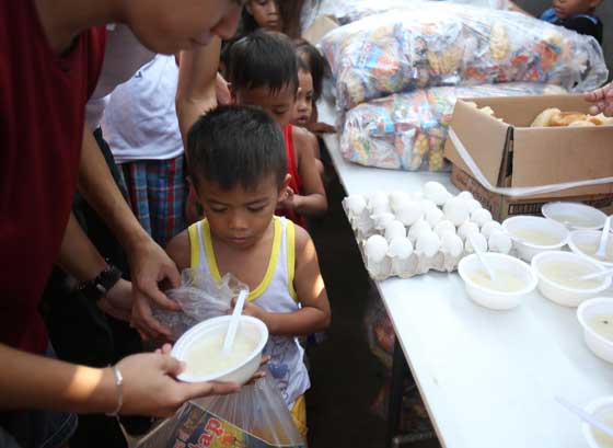 Volunteers hand out porridge to poor children of Parola Compound in Tondo, Manila, during a feeding program sponsored by various groups during the weekend. PHOTO BY RUSSELL PALMA