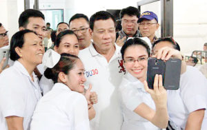 I’M WITH YOU President Rodrigo Duterte poses for a group mobile phone camera photo with health workers at Camp Navarro General Hospital in Zamboanga City on Friday. Duterte promised to raise salaries of the military and the police in a year. MALACAÑANG PHOTO