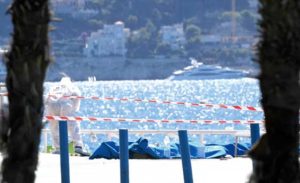 GRIM TASK A forensic expert examines dead bodies covered with a blue sheet on the Promenade des Anglais seafront in the French Riviera city of Nice.  AFP PHOTO