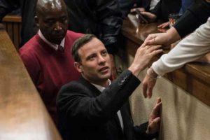 South African Paralympian athlete Oscar Pistorius holds the hand of a relative as he leaves the High Court in Pretoria, on Wednesday after being sentenced to six years in jail for murdering his girlfriend Reeva Steenkamp three years ago.  AFP PHOTO