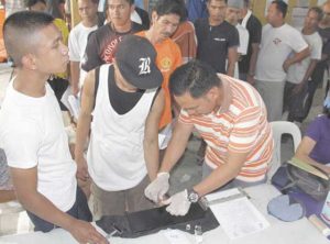 THEY’RE COMING OUT A barangay official gets the fingerprints of a drug suspect who surrendered in Barangay Quirino in Quezon City. PHOTO BY MIKE DE JUAN