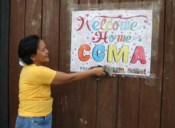 Eloisa Dabu, a supporter of former President Gloria Arroyo, hangs a banner at the gate of the home of the former leader in Lubao, Pampanga. Friends and supporters of Mrs. Arroyo waited for her on Sunday but the former president did not travel to Pampanga supposedly on advice of her doctors. PHOTO BY RUSSELL PALMA