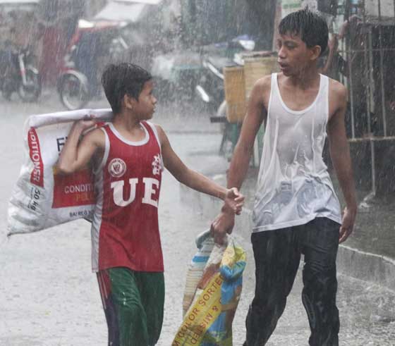 Scavengers walk under the rain while looking for materials they can sell to a junkshop in Quezon City on Sunday. PHOTO BY RUY L. MARTINEZ