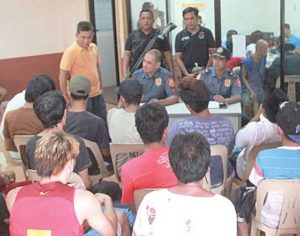 THEY’RE COMING OUT Police Chief Inspector Merine de Guzman and PO3 James Allen Viña talk to illegal drug users who surrendered in Muntinlupa on July 5 at the Putatan Barangay Hall. CONTRIBUTED PHOTO