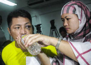 Aneesha gives water to her husband Vhon Tanto who underwent inquest proceedings Tuesday at the Department of Justice. 