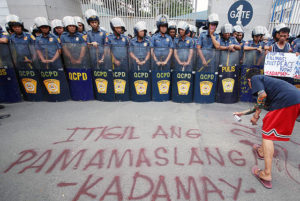 STOP THE KILLINGS Policemen watch as a member of an urban poor group writes a message on a billboard during a rally in front of the police headquarters in Camp Crame to protest the wave of drug killings. PHOTO BY RUY L. MARTINEZ 