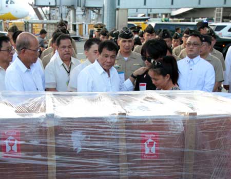 President Rodrigo Duterte looks at the casket bearing the remains of Petty Officer 3 Darwin Espallardo of the Philippine Navy who was killed by a drug dealer in Midsayap, Cotabato. Espallardo and his team were about to serve a search warrant against Commander Madrox but the latter fired at the lawmen. The slain soldier was conferred the medal of valor. With the President were Espallardo’s widow Cleofe and son Dwyndyll. PHOTO BY BENJIE VERGARA