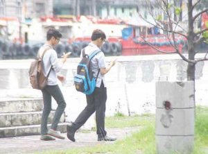 DIGITAL HUNTERS Students are riveted on their smartphones as they hunt digital monsters outside a school in Manila. PHOTO BY LANZ MENDOZA