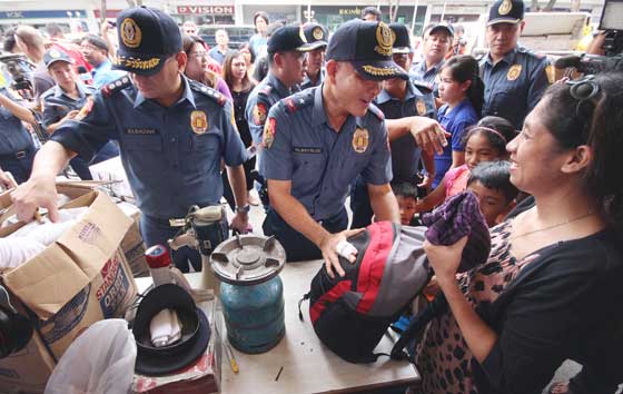 WITH A SMILE Metro Manila police chief Oscar Albayalde (right) and Quezon City police director Guillermo Eleazar check passenger luggage at the Araneta Center Bus Terminal in Quezon City on Friday. Passengers have flocked to the terminal ahead of the long All Saints’ Day weekend. Transport authorities have been placed on heightened alert to ensure passengers’ safety. PHOTO BY RUY L. MARTINEZ 