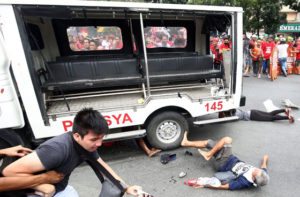 Protesters lie on the ground after being hit by a police van during a rally in front of the US embassy in Manila. AFP Photo