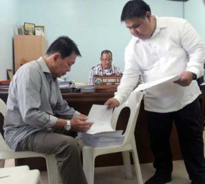 Former Sulu Gov. Sakur Tan (left), assisted by his lawyer, Wendell Sotto, signs his complaint in connection to the 2010 suicide bombing at the Zamboanga Airport which he filed before the office of Prosecutor Ricardo Cabaron (center) in Zamboanga City. PHOTO BY AL JACINTO