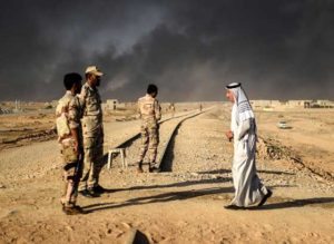 A displaced Iraqi man walks past security forces at a refugee camp on Saturday in the town of Qayyarah, south of Mosul. as an operation to recapture the city of Mosul from the Islamic State group takes place. Iraqi security forces that have ramped up an offensive to retake Mosul continues to battle jihadists.  AFP / BULENT KILIC