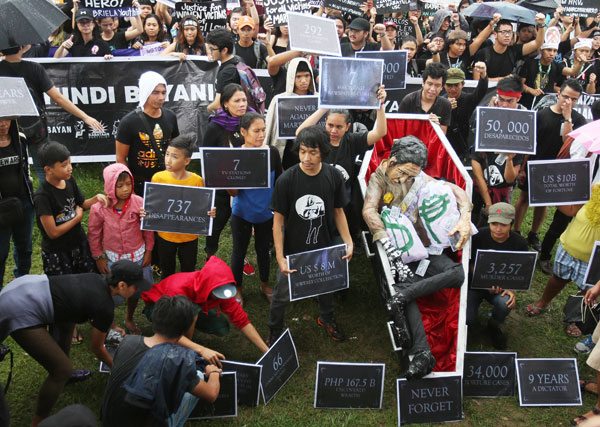 ‘BLACK FRIDAY’ Anti-Marcos protesters surround a mock coffin containing an effigy of the late strongman Ferdinand Marcos at Rizal Park on Friday. Police estimated the crowd at 1,500, but the rally organizers claimed 15,000 people showed up. PHOTO BY RUSSEL PALMA