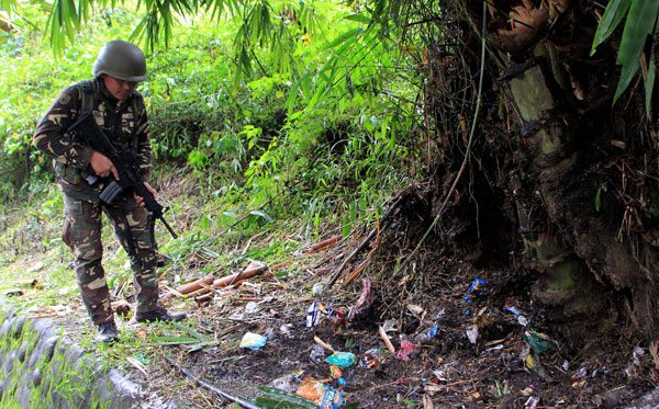 Military troops scour the site of a roadside blast in the village of Matampay in Marawi City, Southern Mindanao