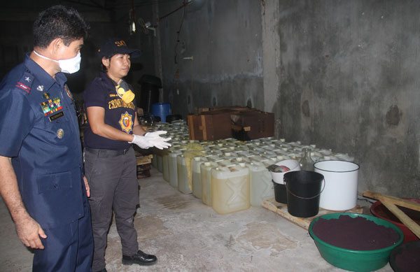  Police investigators inspect chemicals used to manufacture shabu at a warehouse in Palta Small village in Virac, Catanduanes. The shabu laboratory, which was accidentally discovered by Mayor Samuel Laynes during a building inspection, can churn out 100 kilos of the illegal drug per cycle.  PHOTO BY RHAYDZ BARCIA 