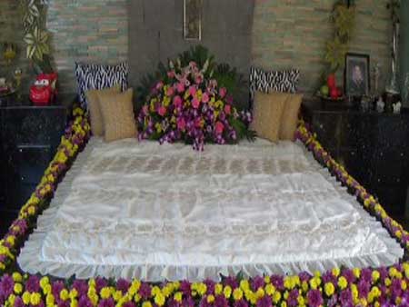 A son’s tomb covered by bed sheet and bedecked with flowers prepared by her mother. PHOTO BY ERNIE B. ESCONDE