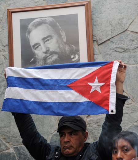 MOURNED, SCORNED A man holds a Cuban flag in front of a portrait of Fidel Castro at the Cuban embassy in Bogota, Colombia, on November 26, a day after the former Cuban president died in Havana at age 90. AFP PHOTO BY GUILLERMO LEGARIA