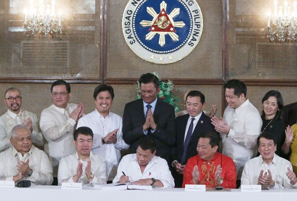 FIRST BUDGET President Rodrigo Duterte signs the P3.35-trillion 2017 national budget in the presence of lawmakers. Beside the President are Senate President Aquilino Pimentel 3rd (seated, left) and House Speaker Pantaleon Alvarez (seated, right). PHOTO BY RENE H. DILAN