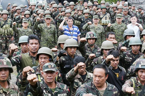 ONE WITH THE TROOPS President Rodrigo Duterte raises his clenched fist along with members of the Philippine Army’s 103rd Brigade in Lumbayanague, Lanao del Sur on Wednesday. Duterte pushed through with the visit despite the blast that injured seven presidential guards and two others on Tuesday. MALACAÑANG 