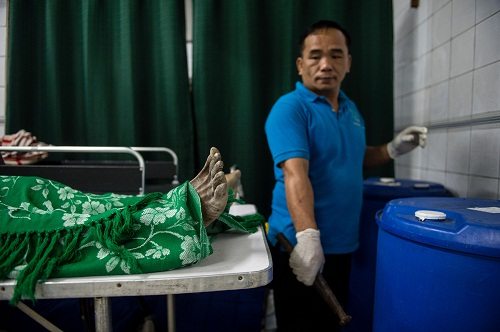 Embalmer Alejandro Ormeneta gets formalin from a drum and prepares embalming instruments before operating on a body in the morgue of the Veronica Memorial Chapel in Manila. AFP PHOTO