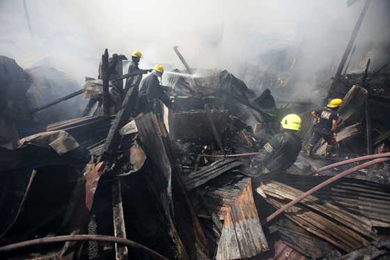 Firemen blast water in a residential area in Barangay Tambo, Parañaque City on Sunday, following a blaze that affected 50 houses. PHOTO BY RUSSELL PALMA