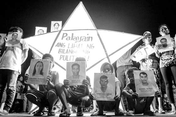 Families of ‘political detainees’ stand in front of a giant lantern as they hold a protest to mark the ‘International Day of Solidarity with Political Prisoners’ in Manila. PHOTO BY DJ DIOSINA